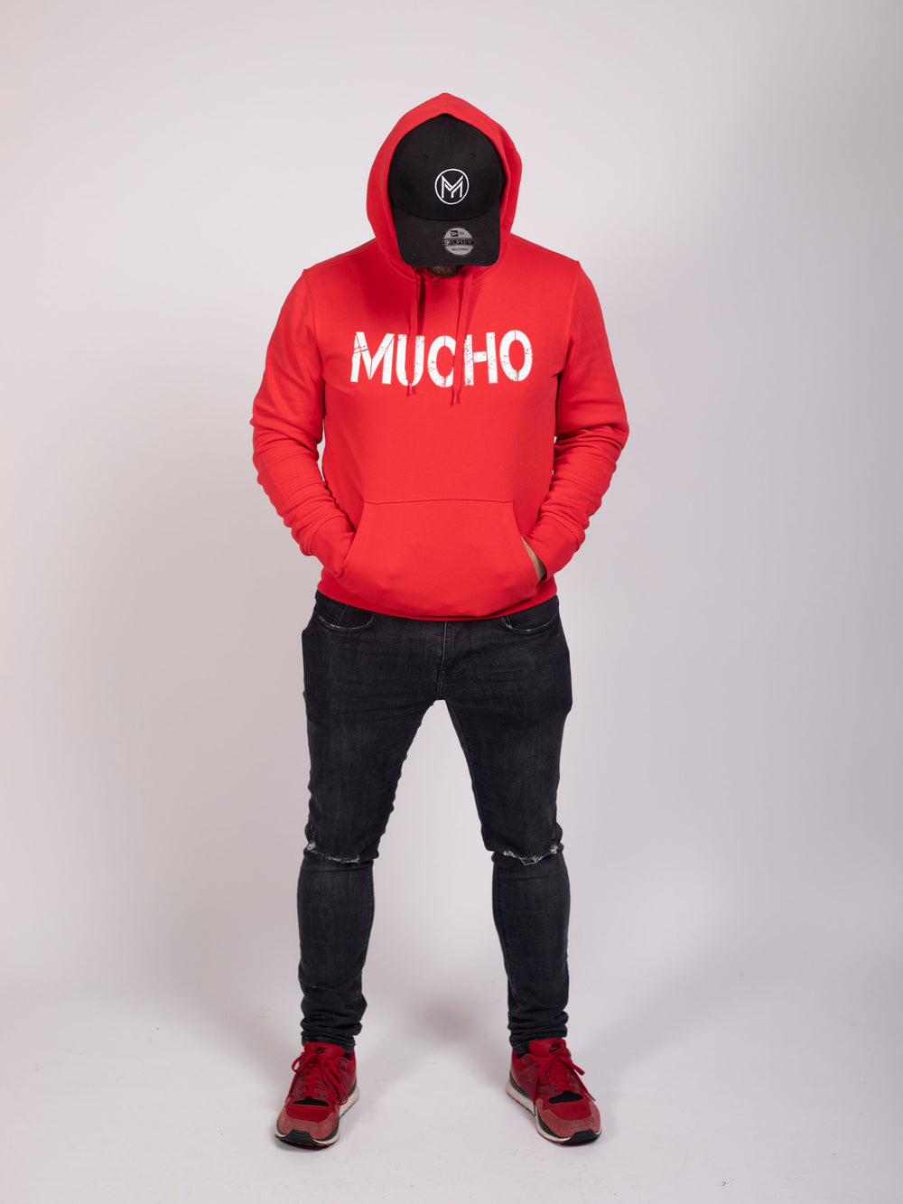 Homme en sweat à capuche rouge avec logo Mucho imprimé et pantalon noir